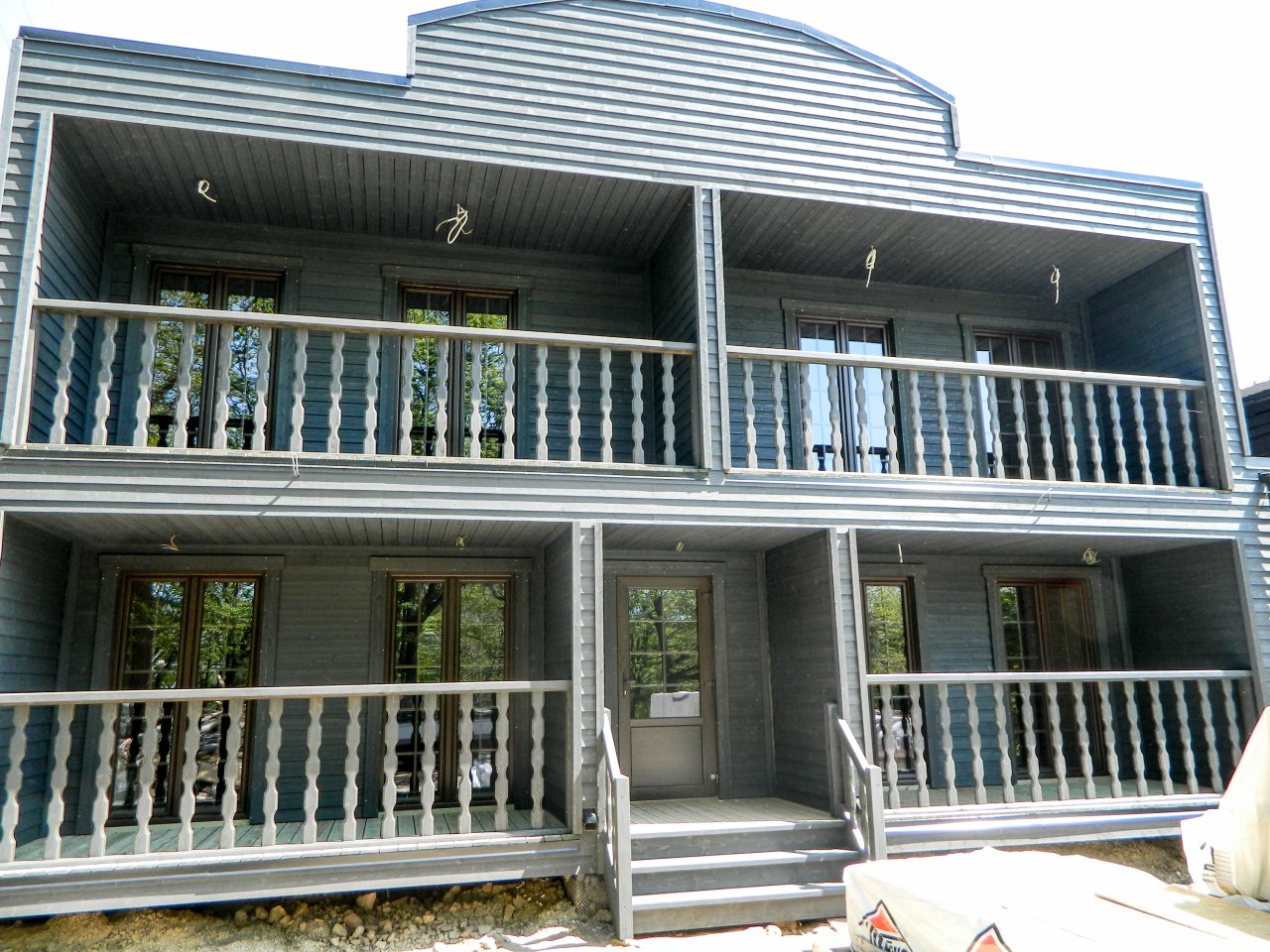 Western-style two-storey timber building with covered balconies and wood cladding in Belgium.