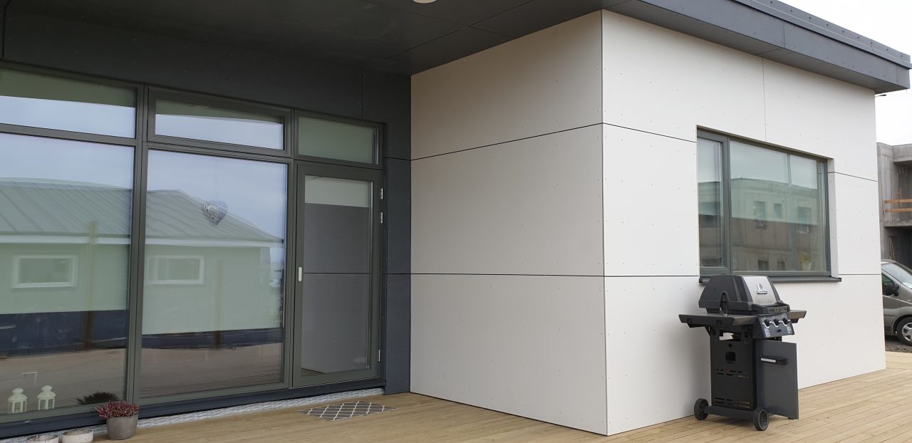 Close-up of entrance area on a modern Icelandic house showing white façade panels and a glass door.