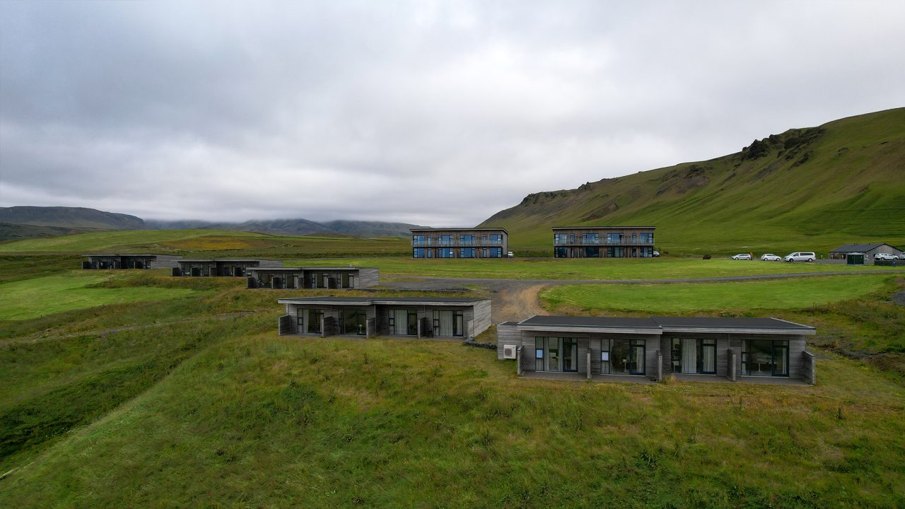Row of coastal hotel cabins in Iceland near the black-sand beach, set on open terrain with panoramic views.