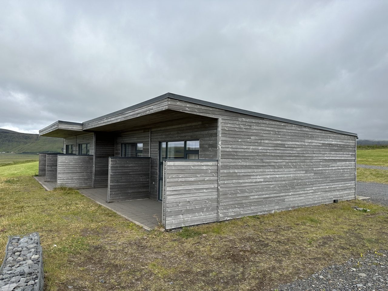 Coastal hotel cabin in Iceland with grey timber cladding, covered entrance, and private outdoor area.