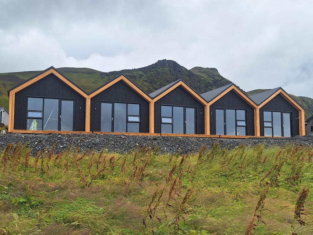 Row of gable-fronted rental units at Black Beach 3 in Suðurland, Iceland, with panoramic glazing.