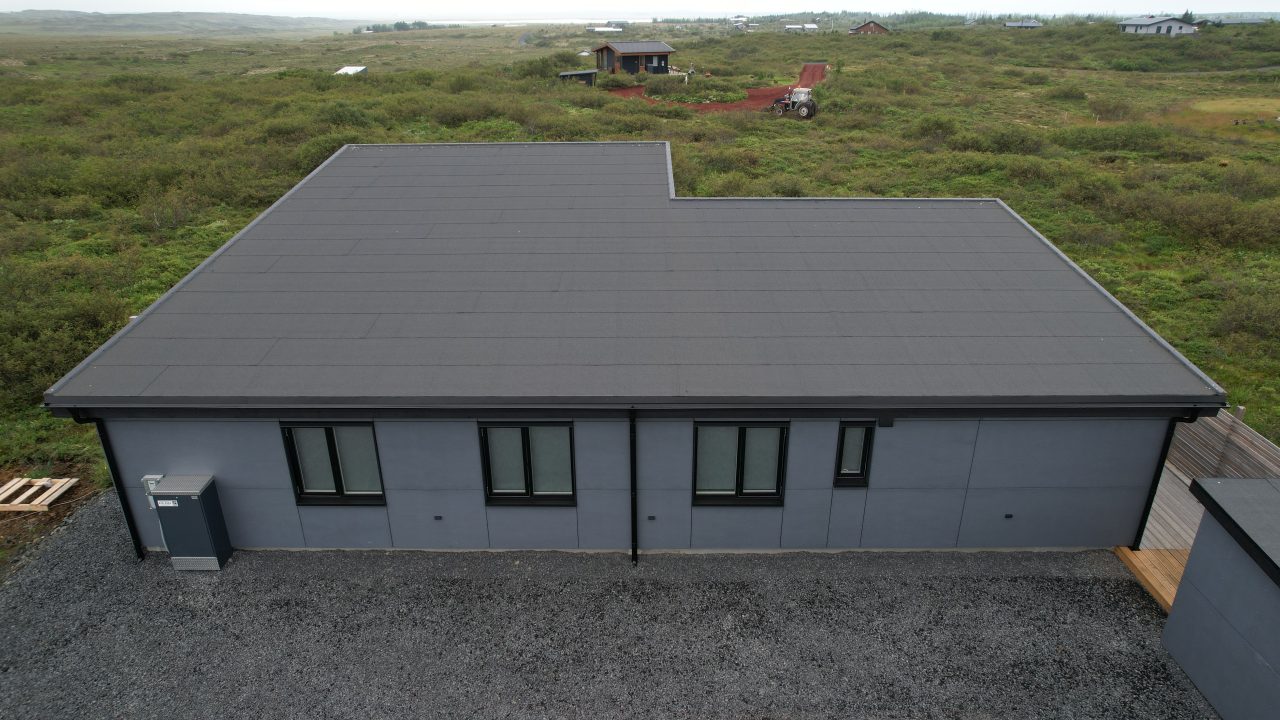 Rear elevation of a modern Icelandic house with grey exterior cladding and multiple windows.