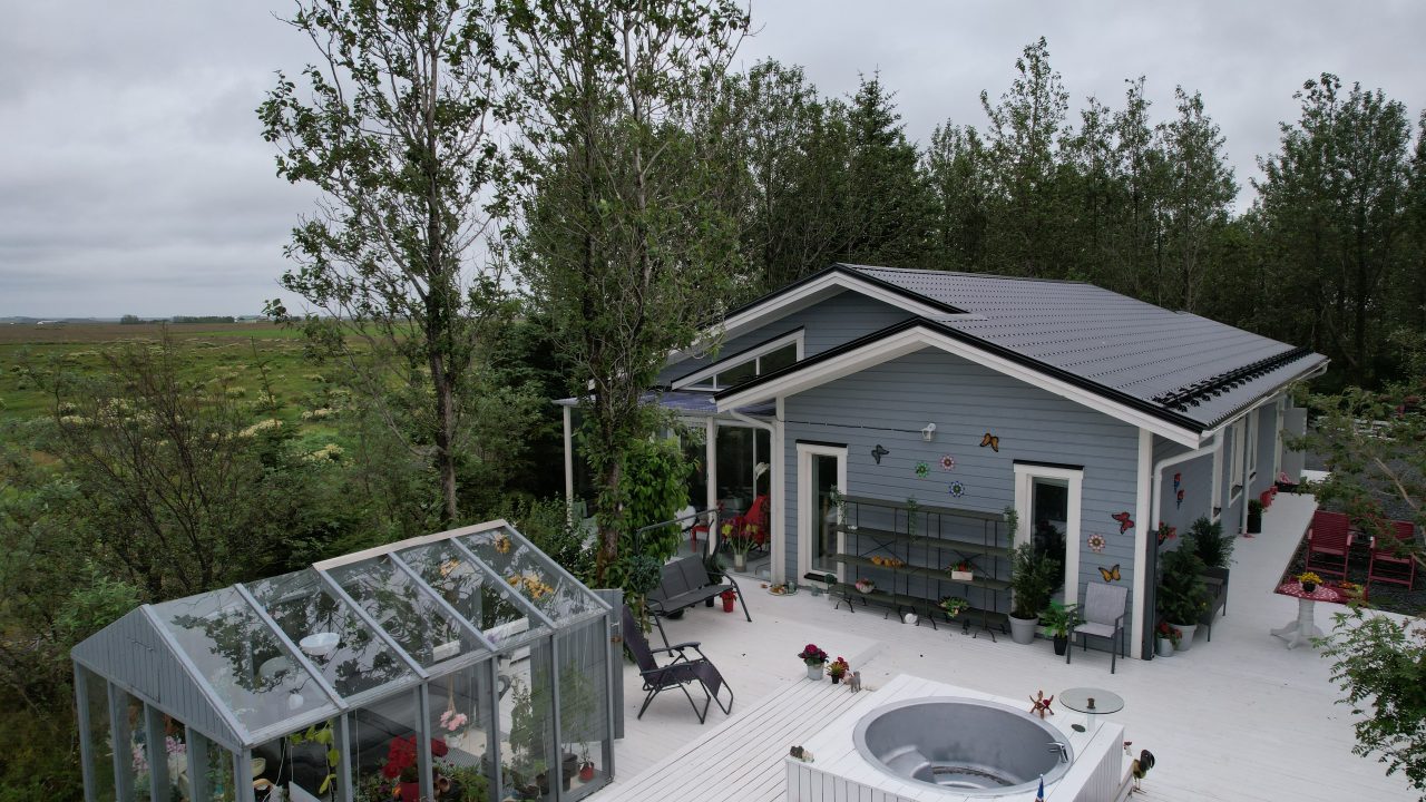 Terrace view of the Lagan standard-design house in Iceland with outdoor seating and surrounding trees.