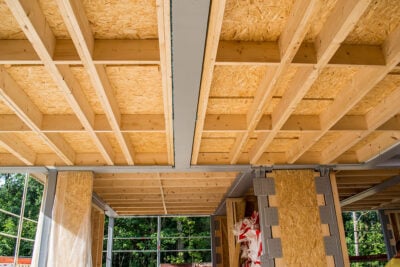 Exposed timber-frame ceiling structure with OSB roof panels inside a building under construction.