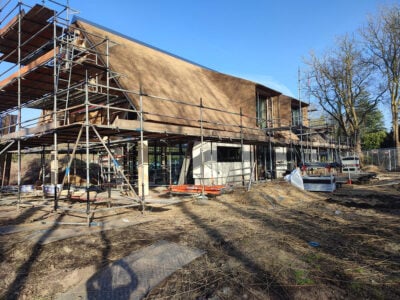 Local roofing tradesmen installing a thatched roof on a timber-frame house.